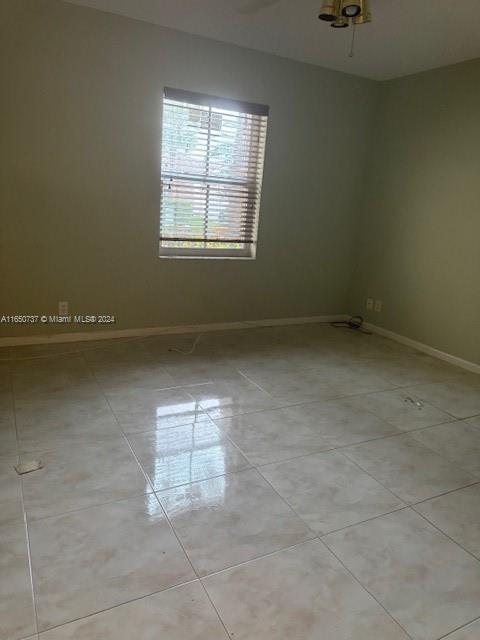 spare room featuring light tile patterned flooring and baseboards