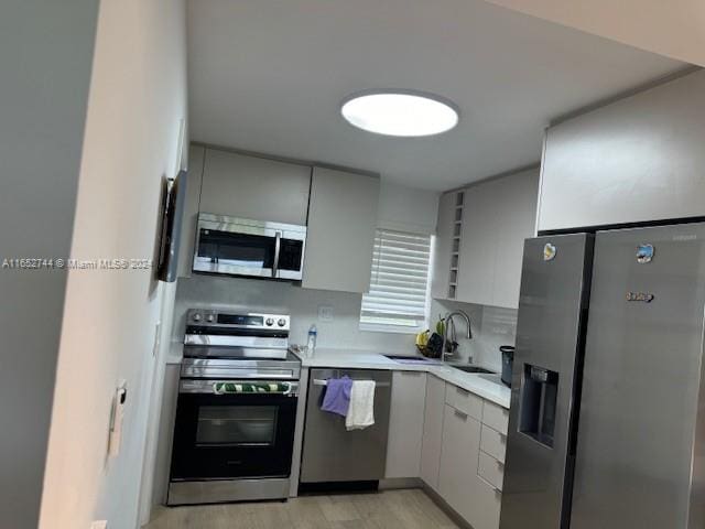 kitchen featuring stainless steel appliances, light hardwood / wood-style floors, and sink