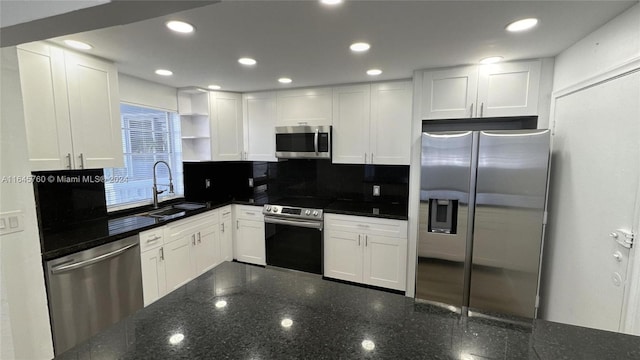 kitchen featuring white cabinets, stainless steel appliances, and dark stone counters