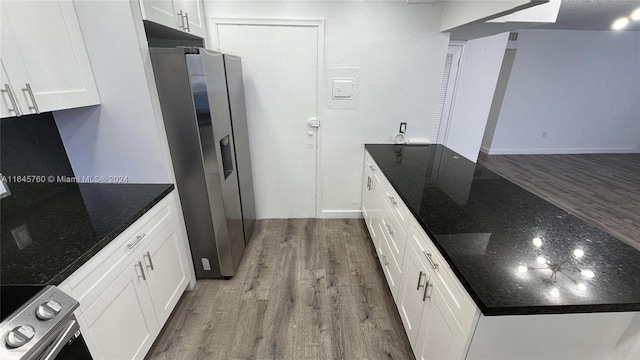 kitchen with white cabinetry, stainless steel appliances, wood-type flooring, and dark stone counters