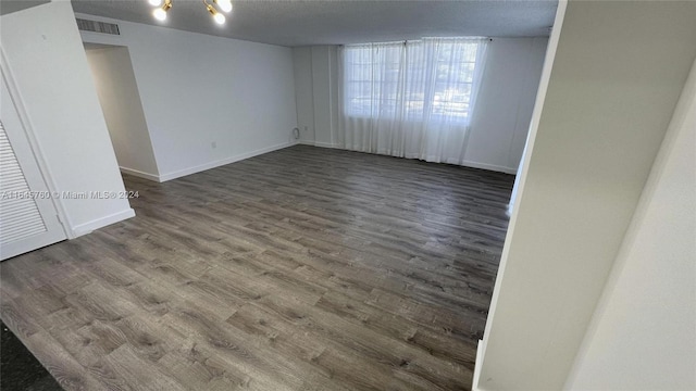 unfurnished room with dark hardwood / wood-style floors, a chandelier, and a textured ceiling