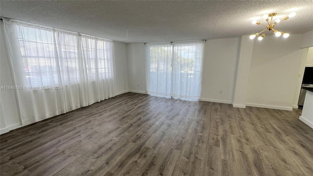 unfurnished living room with a textured ceiling, dark hardwood / wood-style floors, and an inviting chandelier