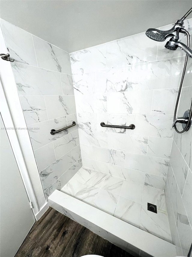 bathroom featuring a tile shower and wood-type flooring