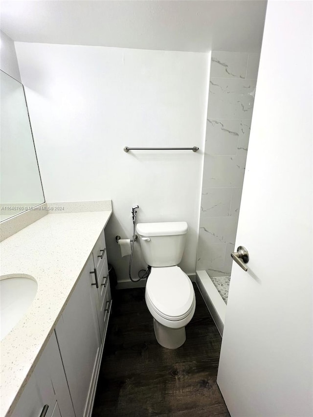 bathroom with vanity, hardwood / wood-style floors, toilet, and tiled shower