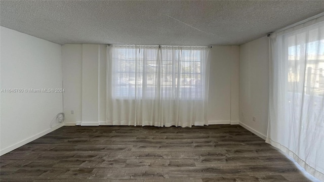 empty room with a textured ceiling and dark hardwood / wood-style flooring