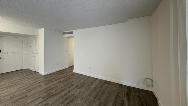 spare room featuring a textured ceiling and dark hardwood / wood-style flooring