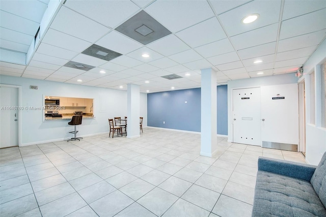 basement featuring a drop ceiling and light tile patterned floors