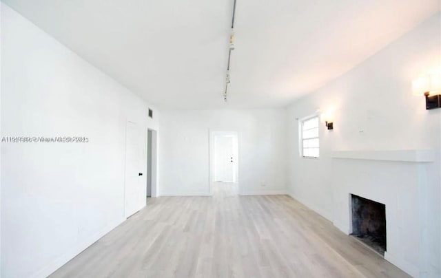 unfurnished living room with rail lighting and light hardwood / wood-style floors