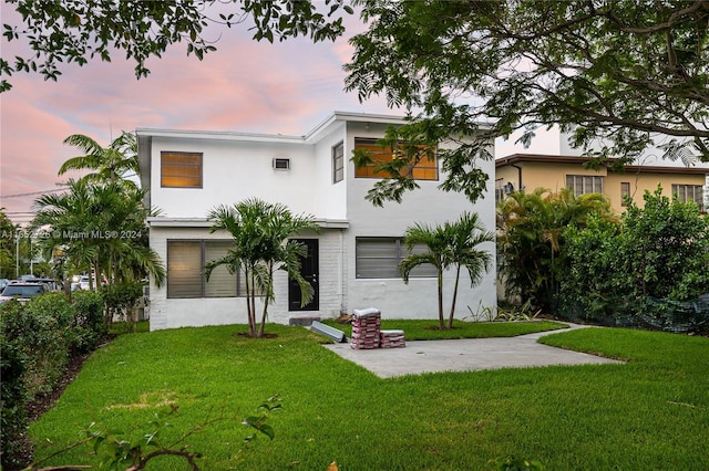 back of property at dusk featuring a yard, stucco siding, and a patio