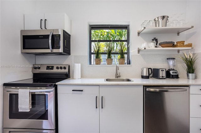 kitchen with a sink, stainless steel appliances, white cabinets, and decorative backsplash