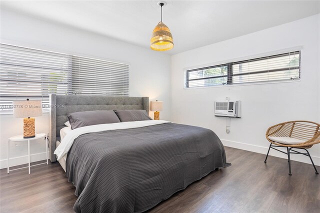 bedroom featuring a wall mounted air conditioner, baseboards, and wood finished floors