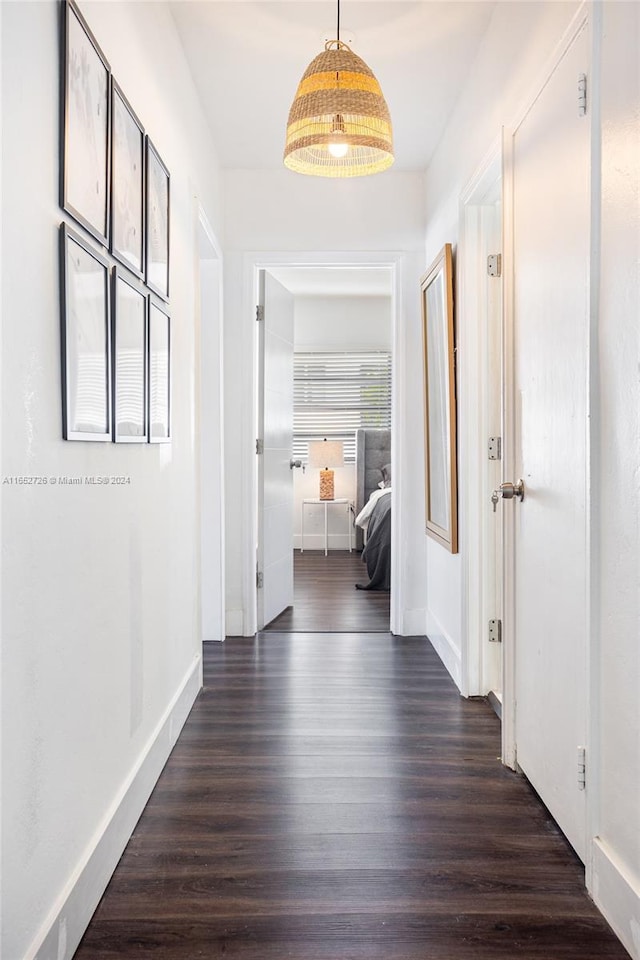 hallway featuring dark wood-type flooring and baseboards