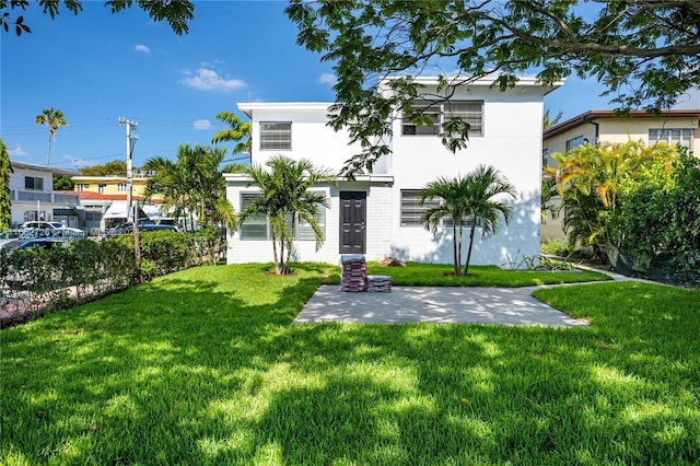 rear view of house featuring stucco siding, a lawn, and a patio area