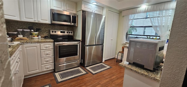 kitchen with tasteful backsplash, dark wood-type flooring, stainless steel appliances, white cabinetry, and stone counters