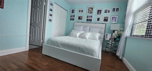 bedroom with dark hardwood / wood-style flooring and a closet