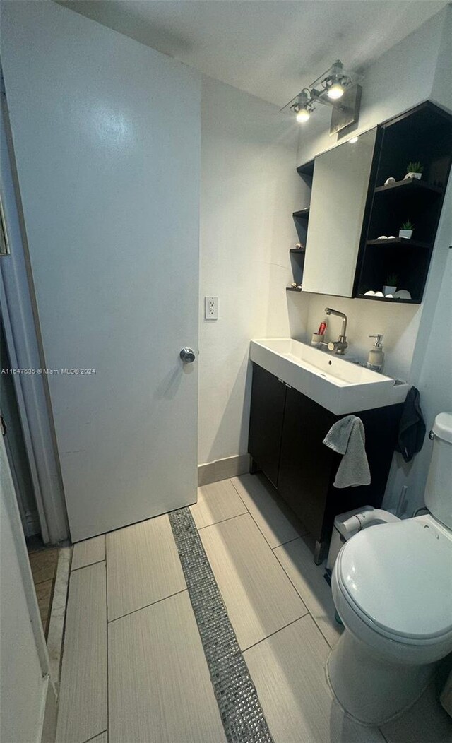 bathroom with tile patterned flooring, vanity, and toilet