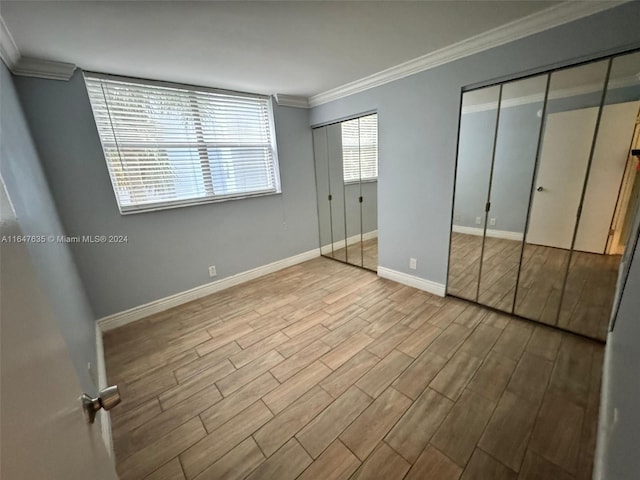 unfurnished bedroom with light hardwood / wood-style flooring, multiple closets, and ornamental molding