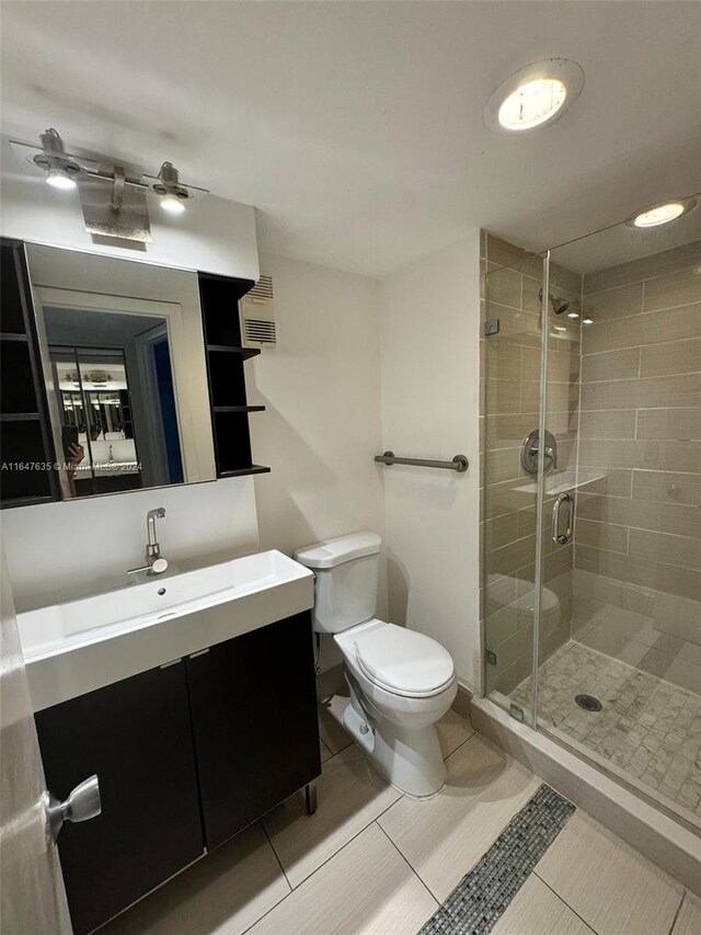 bathroom featuring vanity, a shower with shower door, toilet, and tile patterned floors