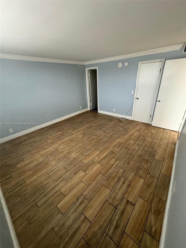 unfurnished bedroom with hardwood / wood-style floors and crown molding