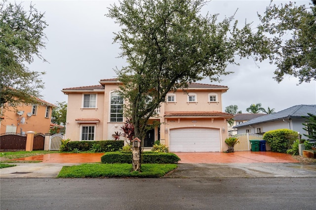 mediterranean / spanish-style home featuring decorative driveway, a gate, a tiled roof, and stucco siding