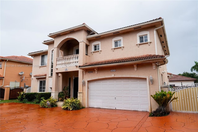 mediterranean / spanish-style home with a tile roof, an attached garage, a gate, fence, and stucco siding