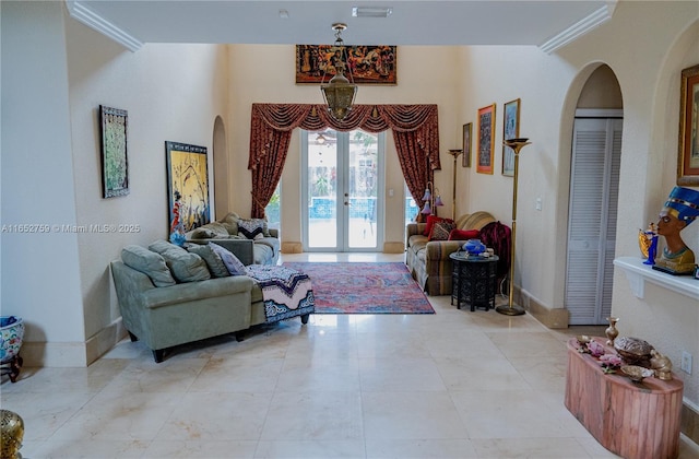 living room featuring baseboards, arched walkways, crown molding, and french doors