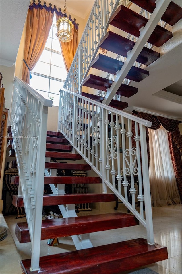 stairs with a chandelier and ornamental molding