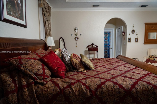 bedroom featuring arched walkways, ornamental molding, and visible vents