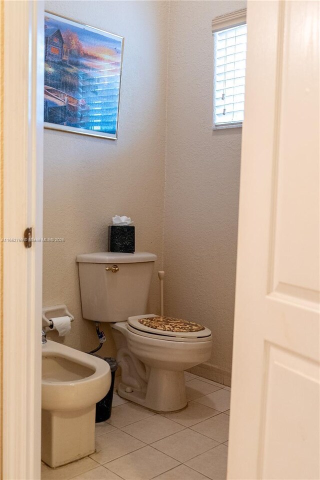 bathroom featuring toilet, a bidet, and tile patterned floors