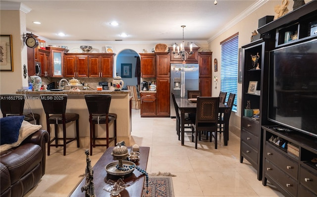 kitchen with arched walkways, a kitchen breakfast bar, appliances with stainless steel finishes, backsplash, and crown molding