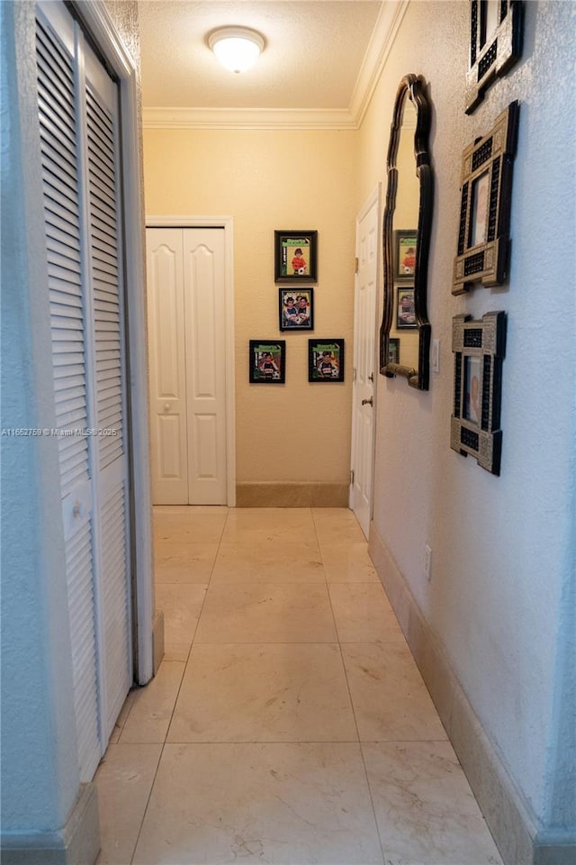 corridor featuring crown molding, baseboards, and light tile patterned floors