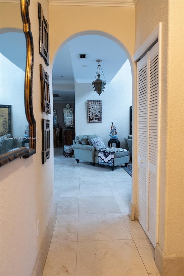 hallway featuring arched walkways, visible vents, and crown molding