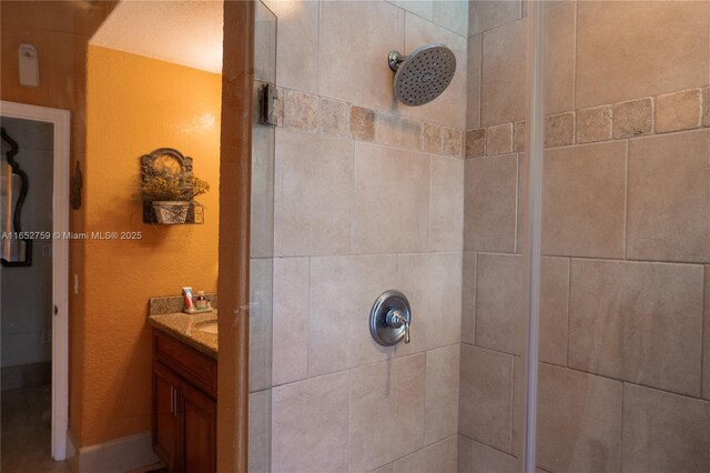 bathroom with tiled shower and vanity