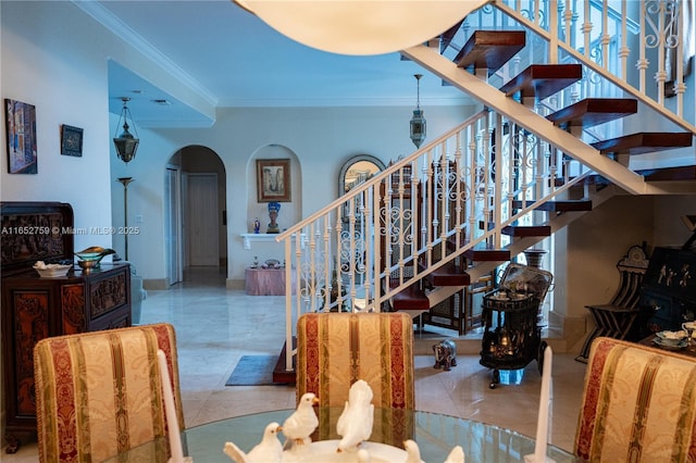 staircase featuring baseboards, arched walkways, and ornamental molding