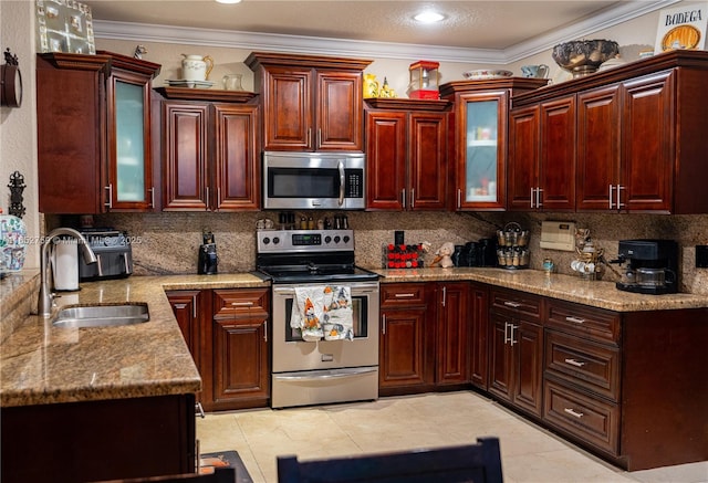 kitchen featuring stainless steel appliances, a sink, ornamental molding, decorative backsplash, and reddish brown cabinets