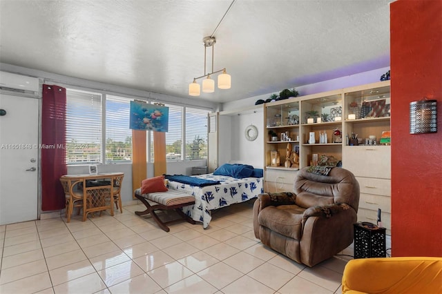 bedroom featuring a wall mounted air conditioner, light tile patterned flooring, and a textured ceiling