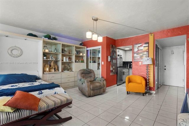 bedroom featuring light tile patterned floors and freestanding refrigerator