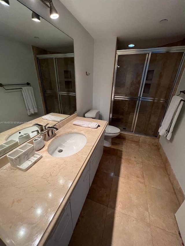 bathroom with tile patterned flooring, vanity, toilet, and a shower with shower door