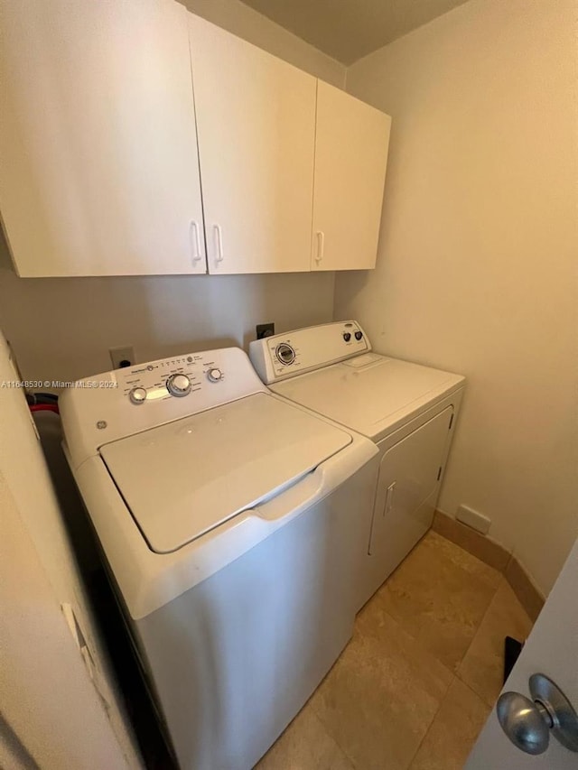 clothes washing area featuring light tile patterned flooring, cabinets, and separate washer and dryer