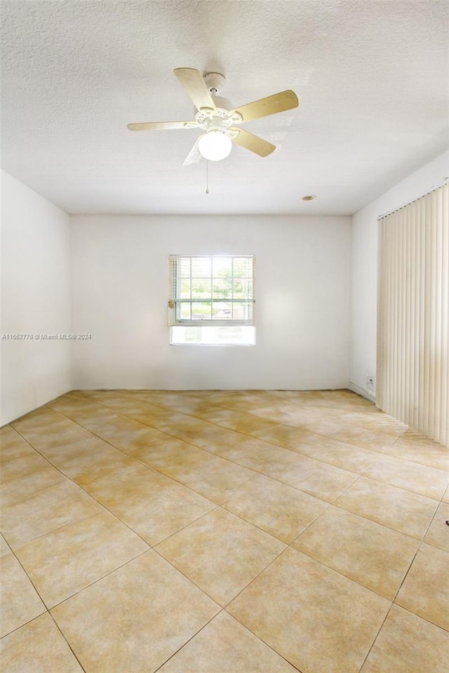 unfurnished room with a textured ceiling, ceiling fan, and light tile patterned floors