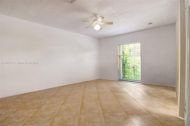 tiled spare room featuring a textured ceiling and ceiling fan