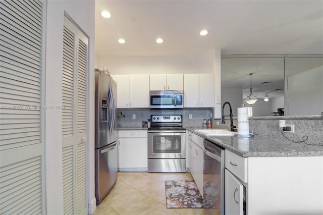 kitchen featuring white cabinets, appliances with stainless steel finishes, stone countertops, sink, and tasteful backsplash