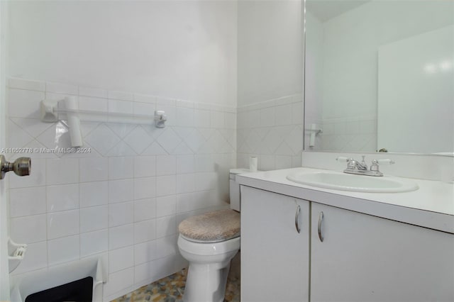 bathroom featuring tile patterned floors, vanity, toilet, and tile walls