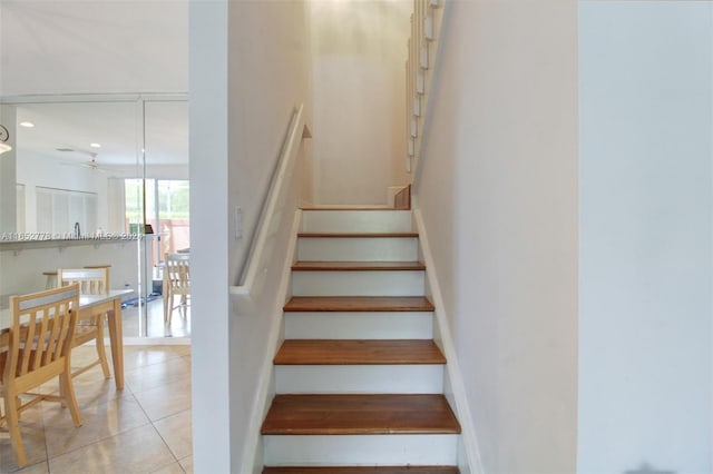 staircase featuring tile patterned flooring and ceiling fan