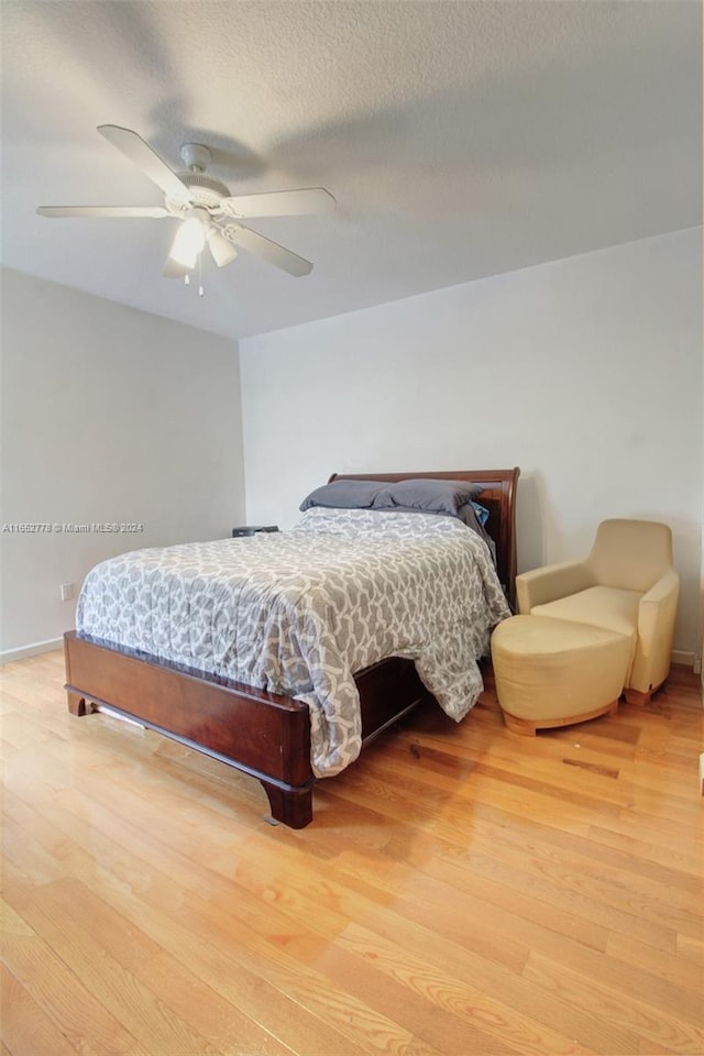 bedroom with light wood-type flooring, a textured ceiling, and ceiling fan