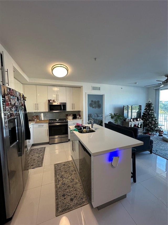 kitchen featuring white cabinets, sink, ceiling fan, light tile patterned floors, and appliances with stainless steel finishes