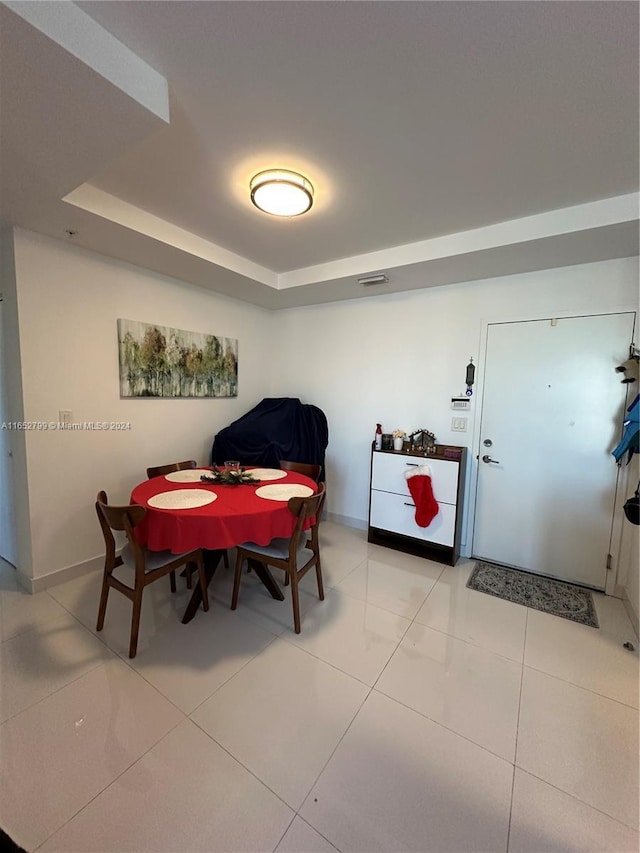 tiled dining area featuring a raised ceiling