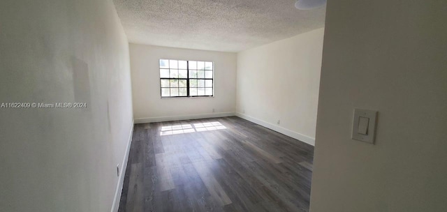 unfurnished room featuring a textured ceiling and dark hardwood / wood-style floors