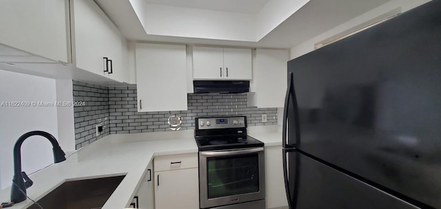 kitchen with stainless steel electric stove, exhaust hood, sink, white cabinets, and black fridge