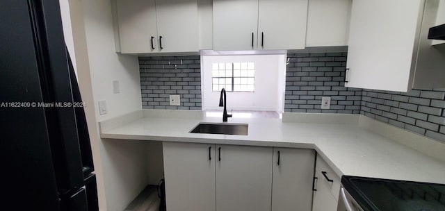 kitchen featuring black fridge, white cabinets, stainless steel range, and sink